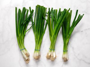Bunches of green onions on a white marble countertop