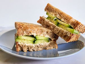 Halved 2-ingredient cucumber sandwich on a plate, with one sandwhich half leaned on another 