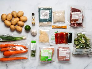 Ingredients from a meal kit arranged on a marble counter